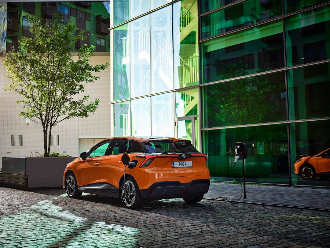 Orange MG 4 EV charging from kerbside wall box in city