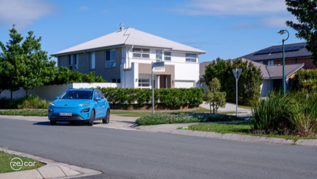 Hyundai Kona Electric driving in residential street and front white seats