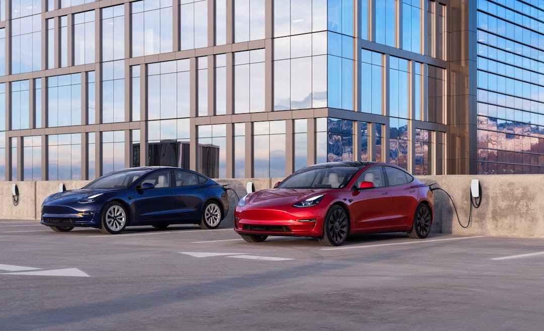 Blue and red Tesla Model 3 charging