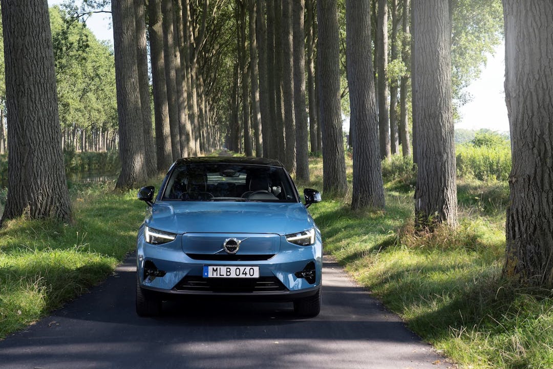Blue Volvo C40 EV driving in forest
