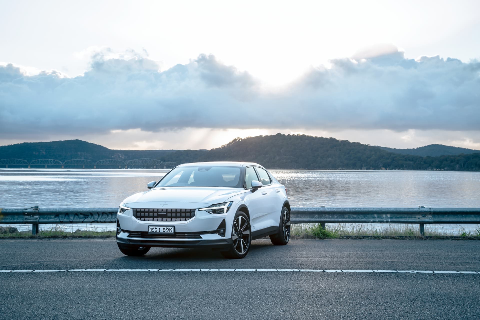 White Polestar 2 electric car in front of lake White Polestar 2 electric car in front of lake