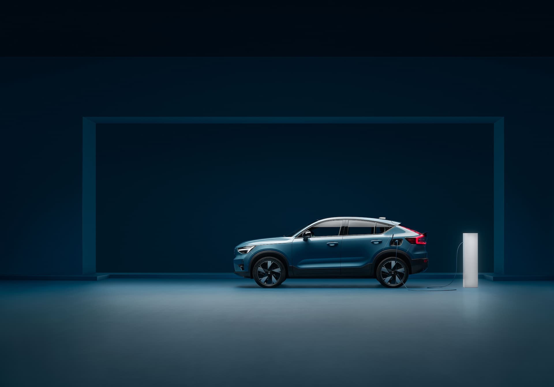 Fjord Blue Volvo C40 Recharge with new 19-inch wheels charging from stand side view Fjord Blue Volvo C40 Recharge with new 19-inch wheels charging from stand side view