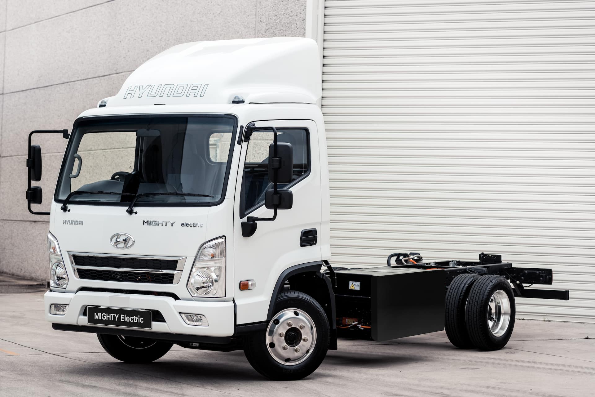 White Hyundai Mighty Electric in front of high rise white wall White Hyundai Mighty Electric in front of high rise white wall