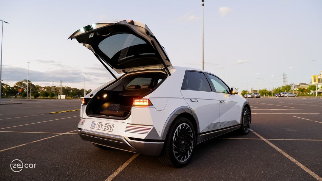White Hyundai Ioniq 5 with boot open and tail lights on in sunset White Hyundai Ioniq 5 with boot open and tail lights on in sunset