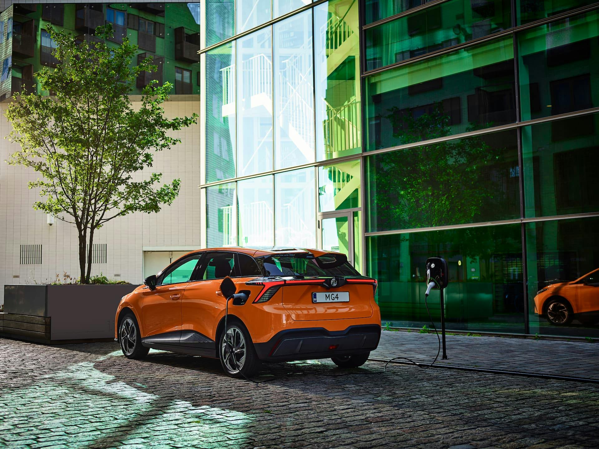 Orange MG 4 charging from city street kerbside AC wall box charger