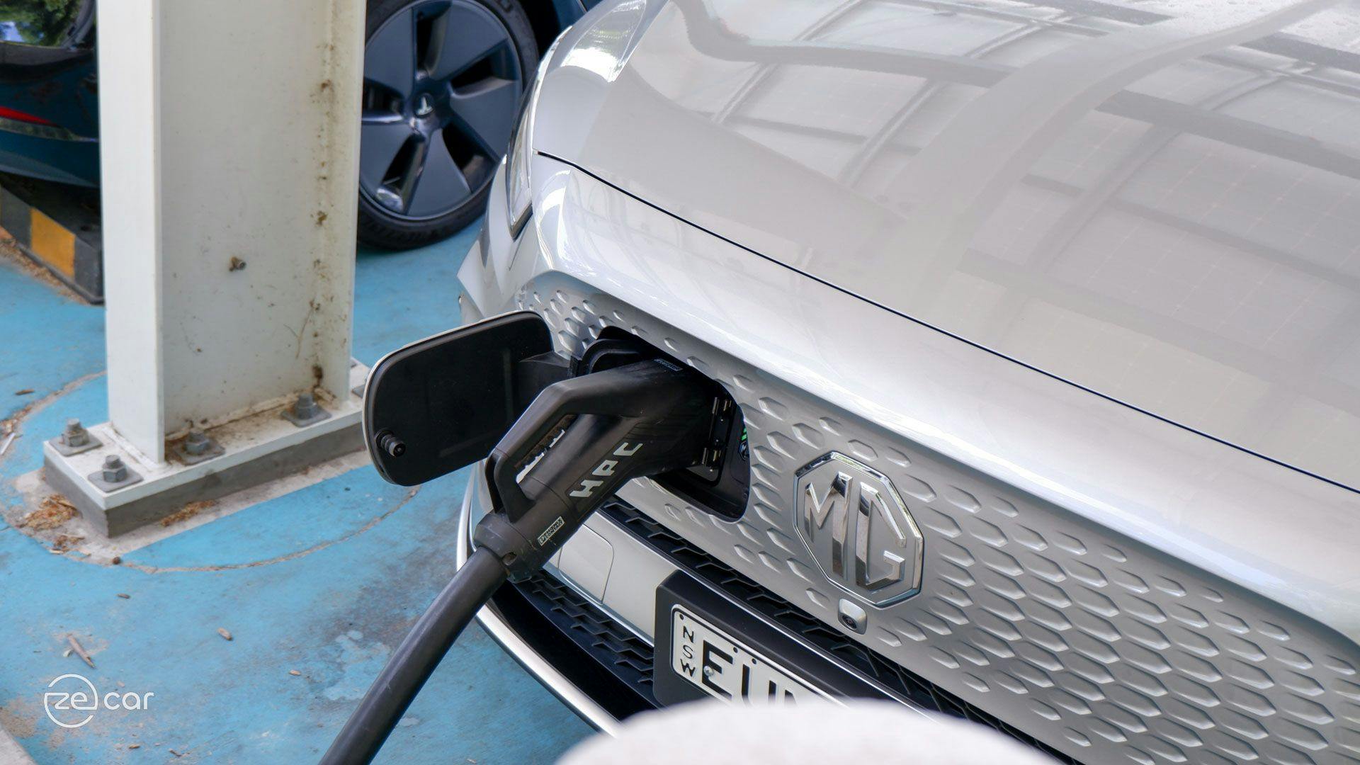 Silver MG ZS EV charging port with Tesla Model 3 behind