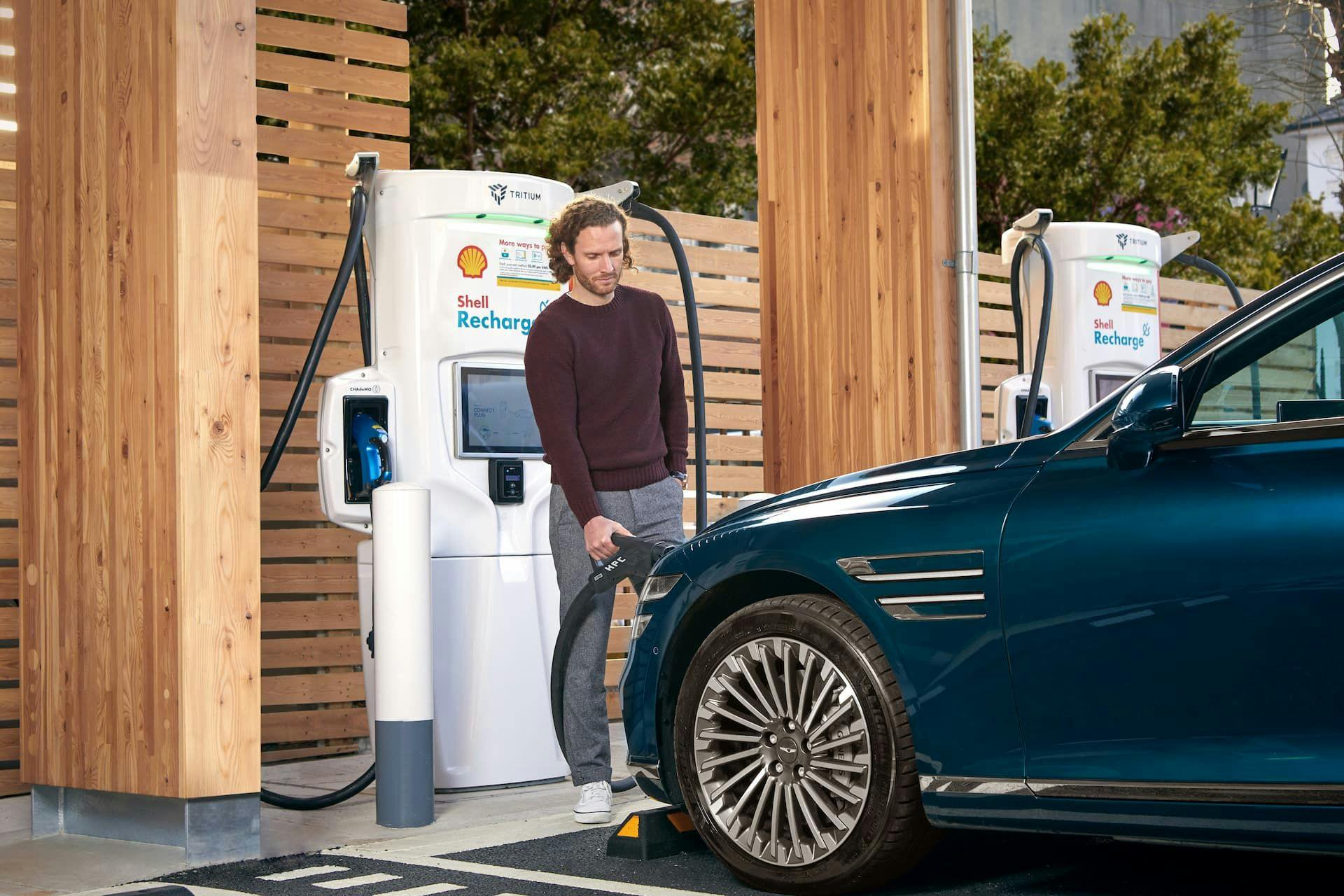 Man plugging in charging cable into Genesis Electrified G80 at Shell Recharge ultra rapid Tritium EV charging station