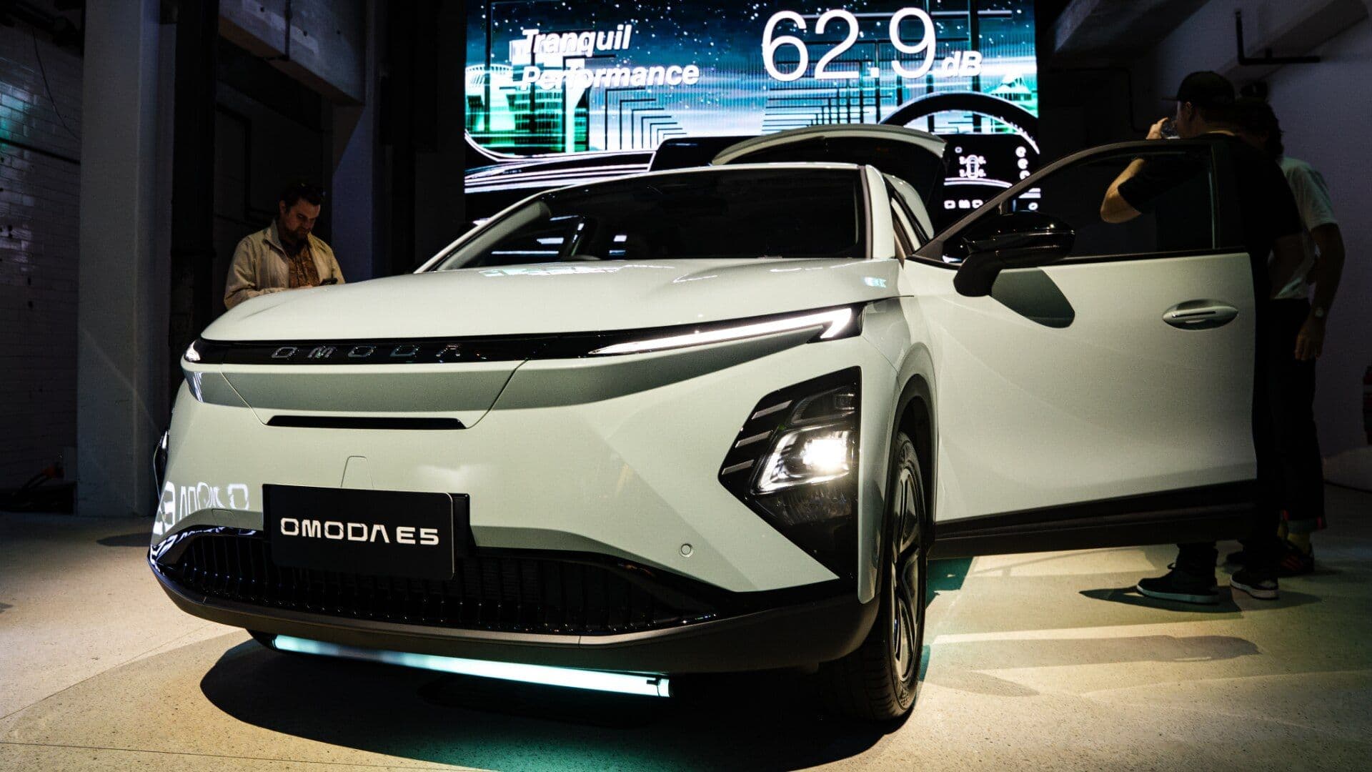 Chery Omoda E5 in teal three quarter view with open doors and trunk at showroom Chery Omoda E5 in teal three quarter view with open doors and trunk at showroom