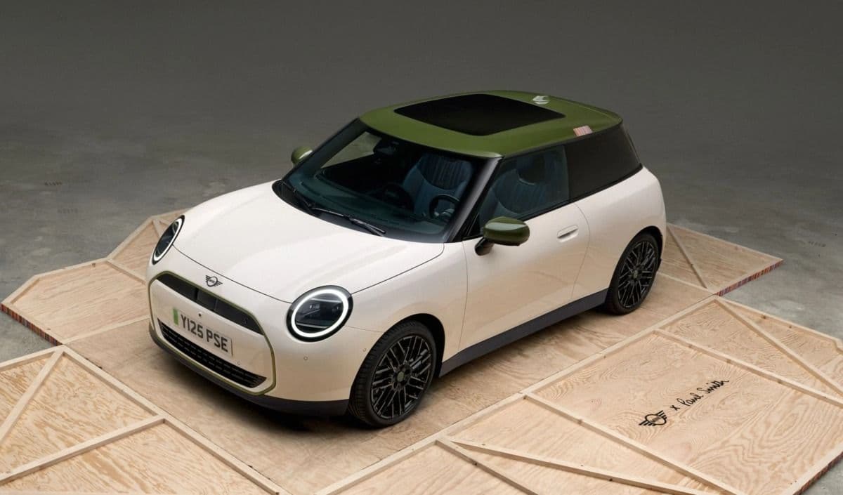 MINI Cooper SE Paul Smith Edition in white with green roof, three-quarter front view on a wooden display platform MINI Cooper SE Paul Smith Edition in white with green roof, three-quarter front view on a wooden display platform