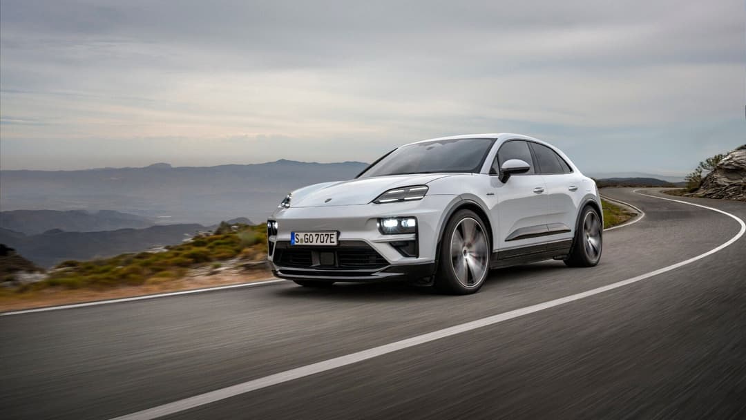 Porsche Macan Turbo in white driving on road three quarter view Porsche Macan Turbo in white driving on road three quarter view