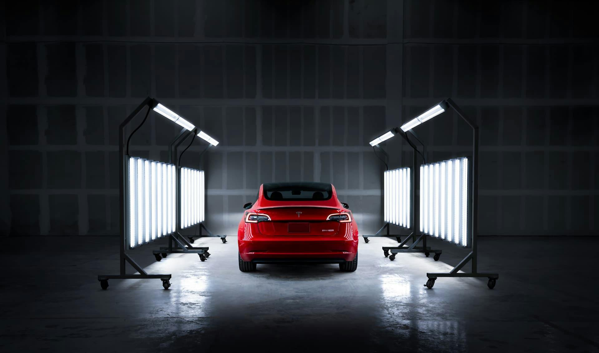 Red Tesla Model 3 rear in factory paint inspection shop