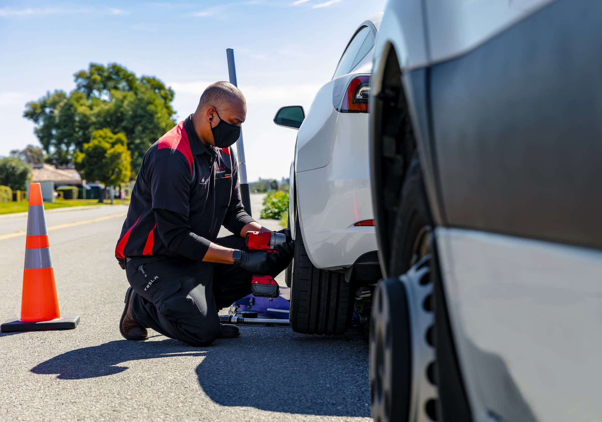 Man replacing Tesla Model 3 tyre beside road Man replacing Tesla Model 3 tyre beside road
