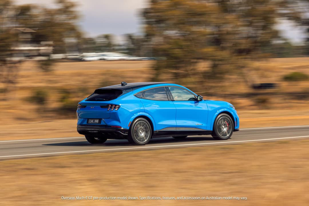 Blue Ford Mustang Mach-E GT driving on track rear view Blue Ford Mustang Mach-E GT driving on track rear view