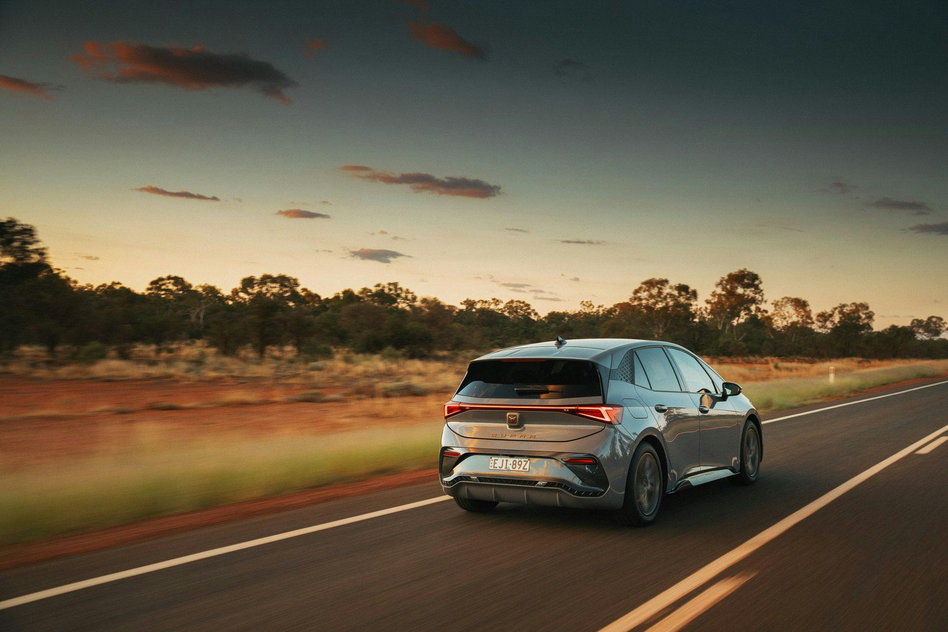 Grey Cupra Born driving in rural Australian sunset with rear tail lights on