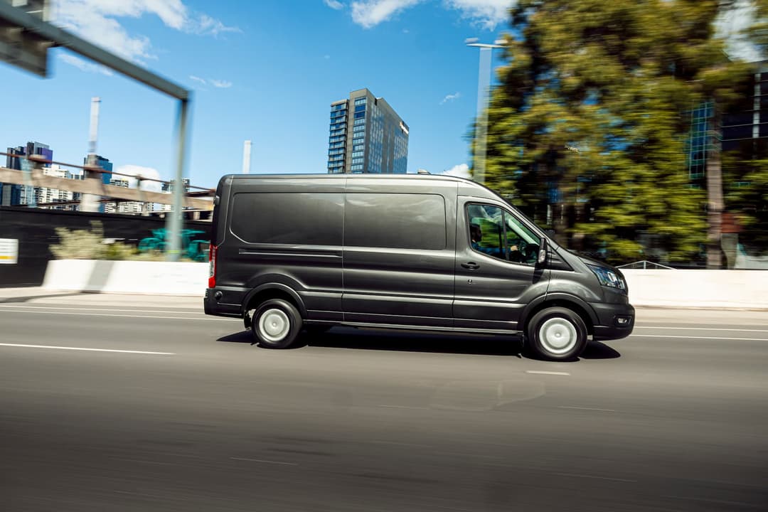 Grey Ford E-Transit driving on city motorway Grey Ford E-Transit driving on city motorway