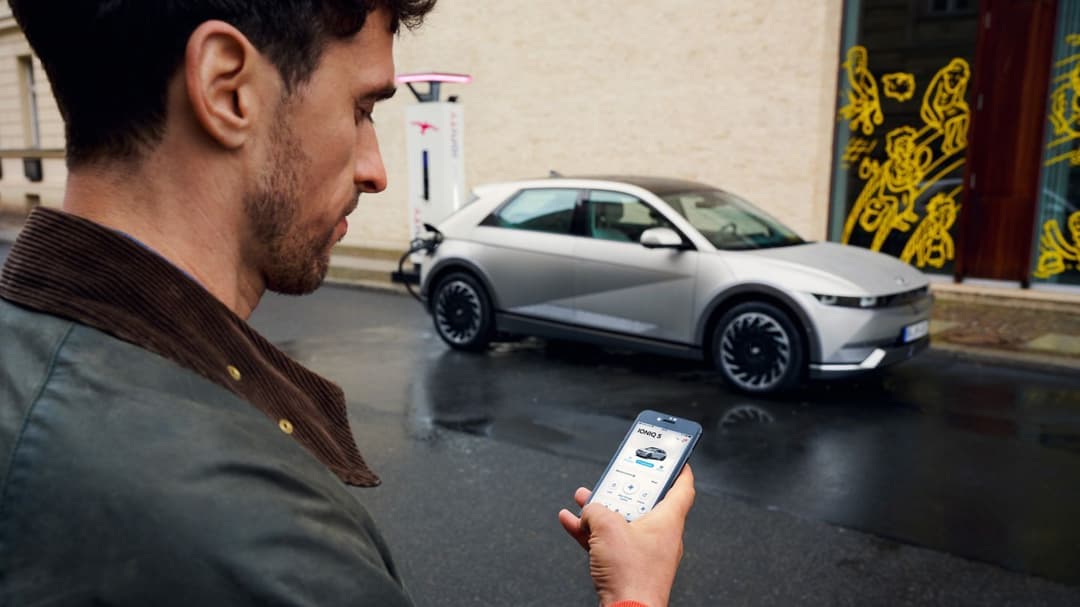 Man using phone in front of charging Hyundai Ioniq 5 Man using phone in front of charging Hyundai Ioniq 5