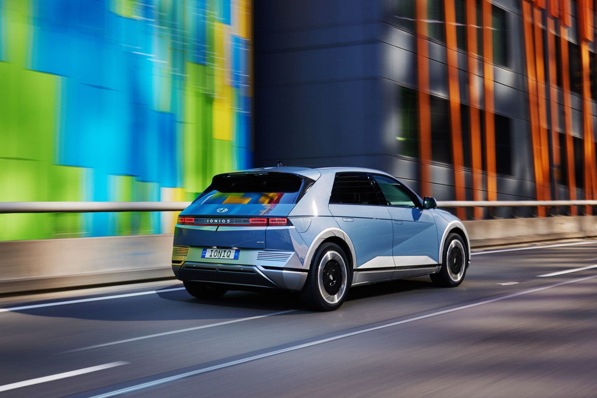 Hyundai Ioniq 5 Lucid blue driving on urban highway rear view Hyundai Ioniq 5 Lucid blue driving on urban highway rear view