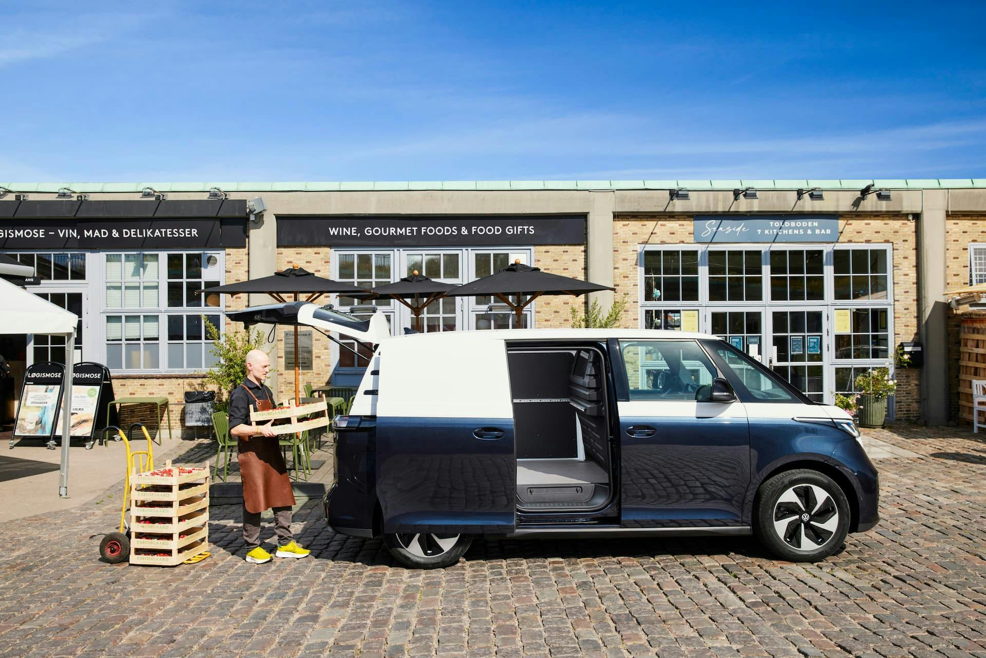 Man puts crates into Volkswagen ID.Buzz Cargo in front of gourmet shop