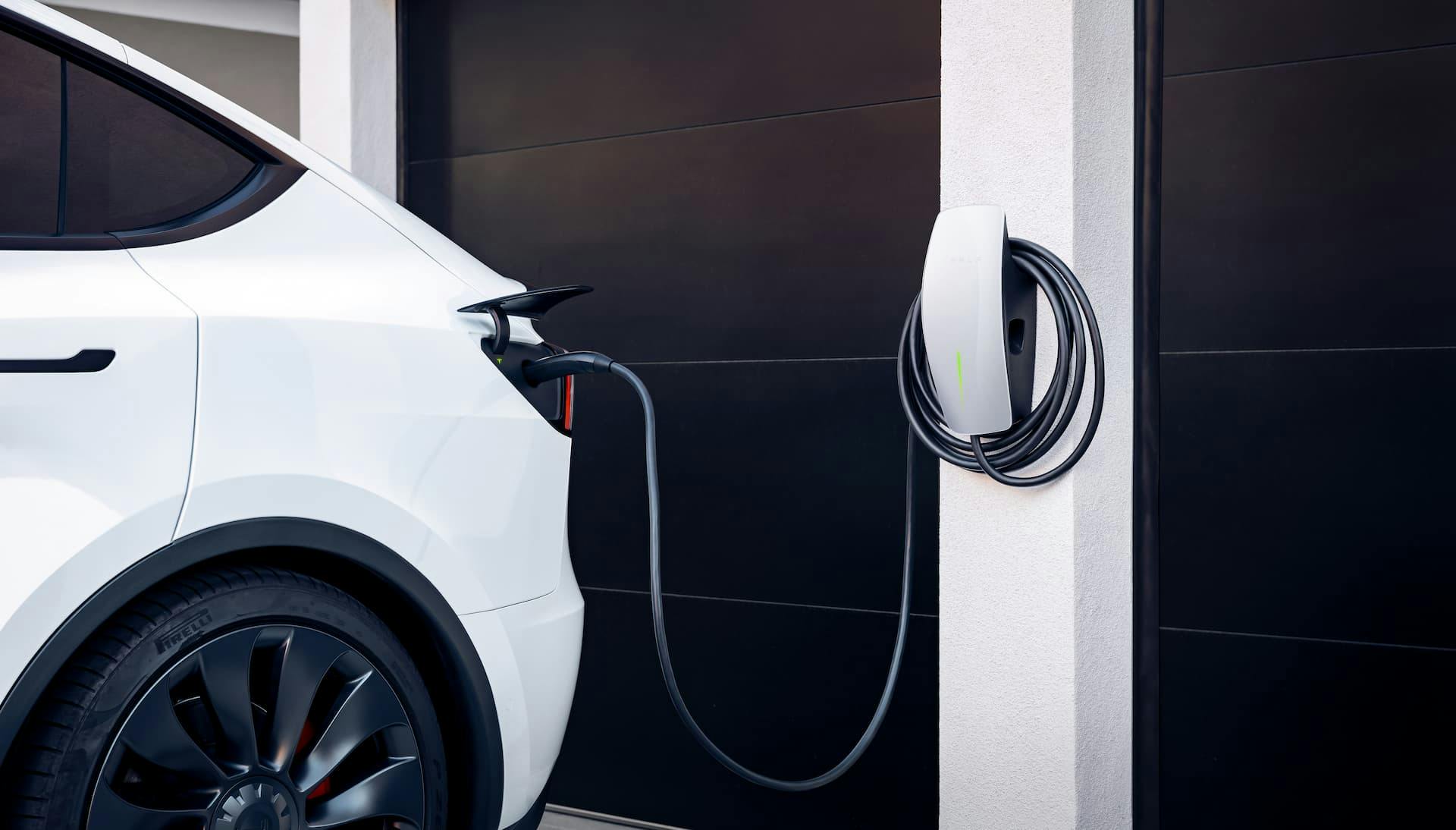 White Tesla Model Y electric SUV charging from home wallbox Tesla Wall Connector