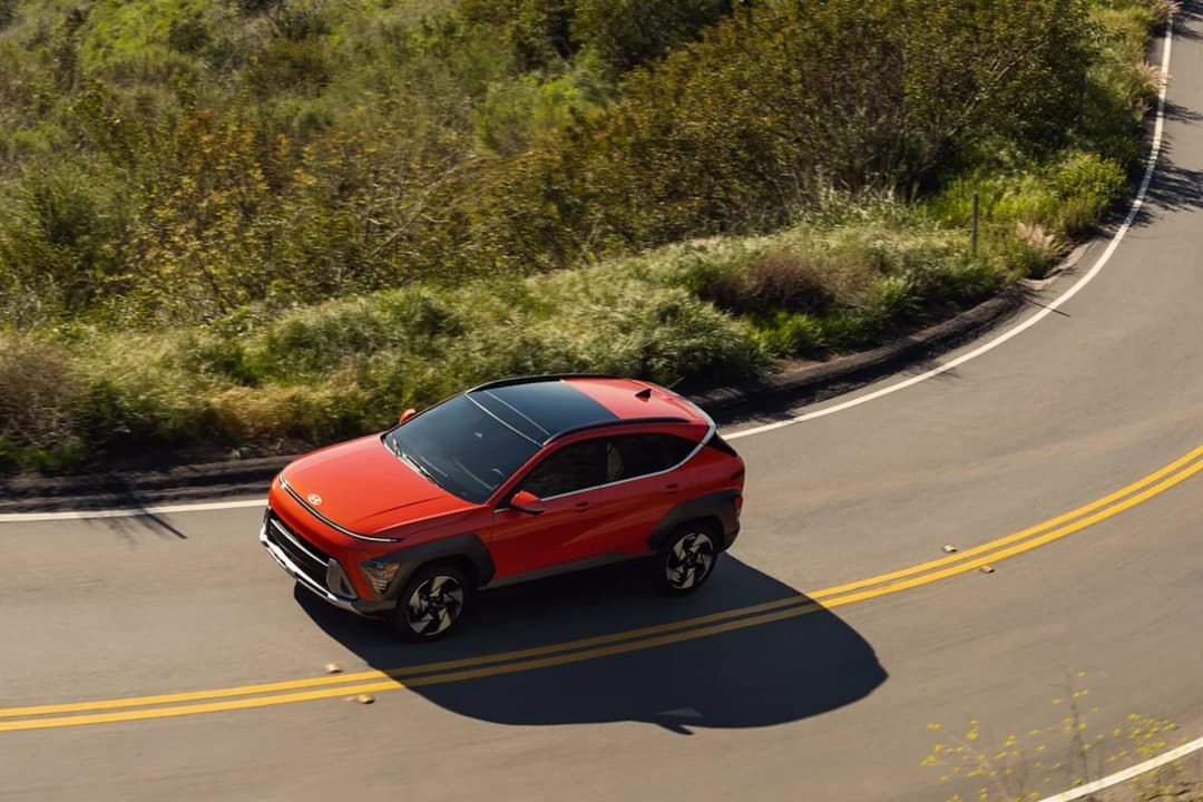 Hyundai Kona in red top view riding at road curve Hyundai Kona in red top view riding at road curve