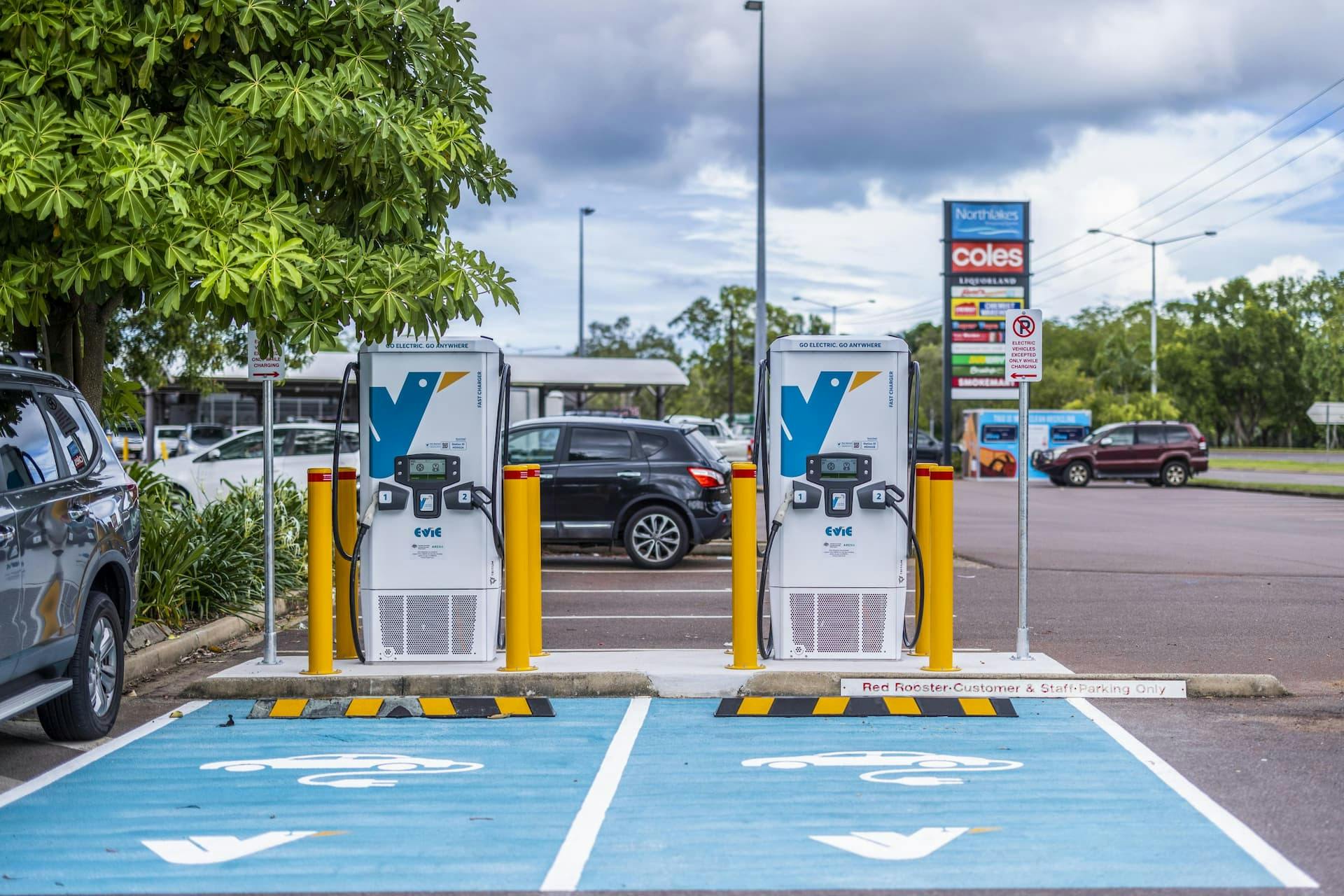 Two Evie Networks fast chargers in Darwin with teal painted charging spots in front of market area