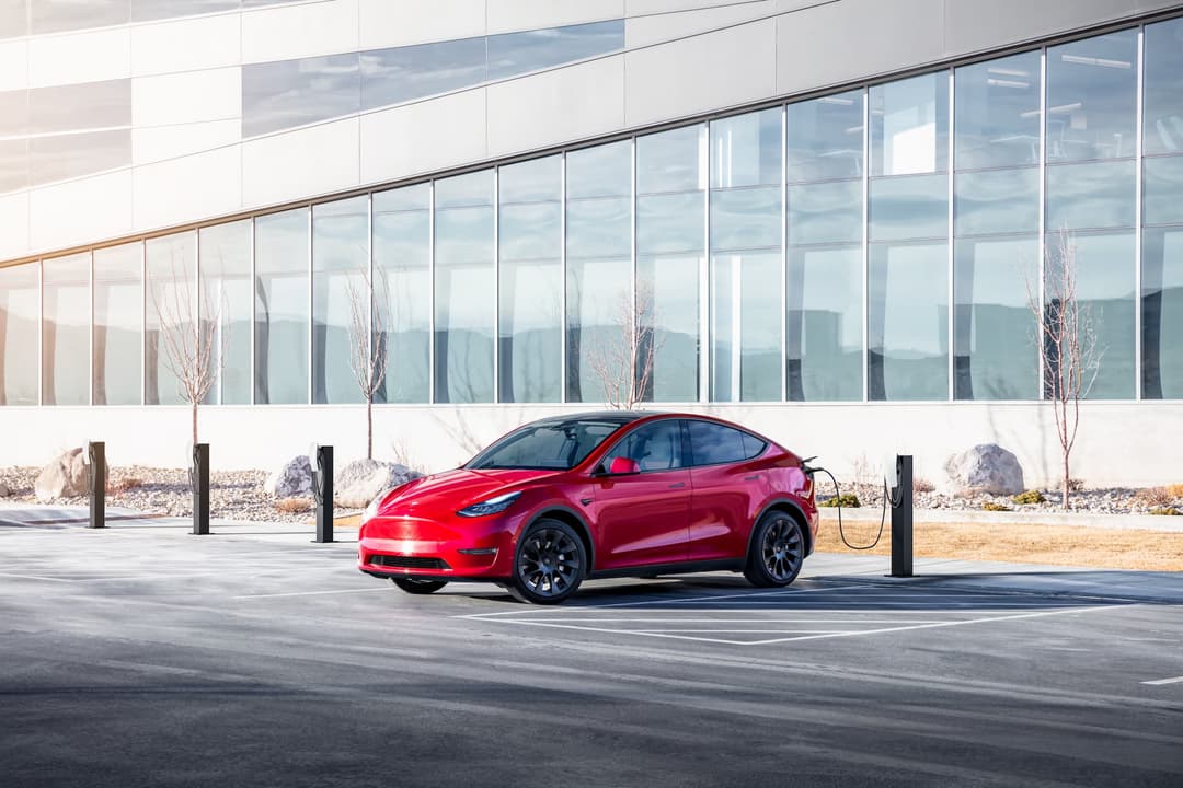 Red Tesla Model Y charging from wall box Red Tesla Model Y charging from wall box