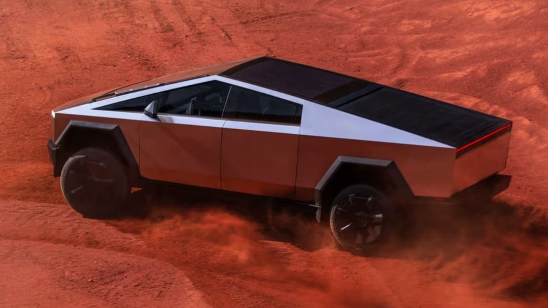 Tesla Cybertruck driving on red-orange desert sand Tesla Cybertruck driving on red-orange desert sand