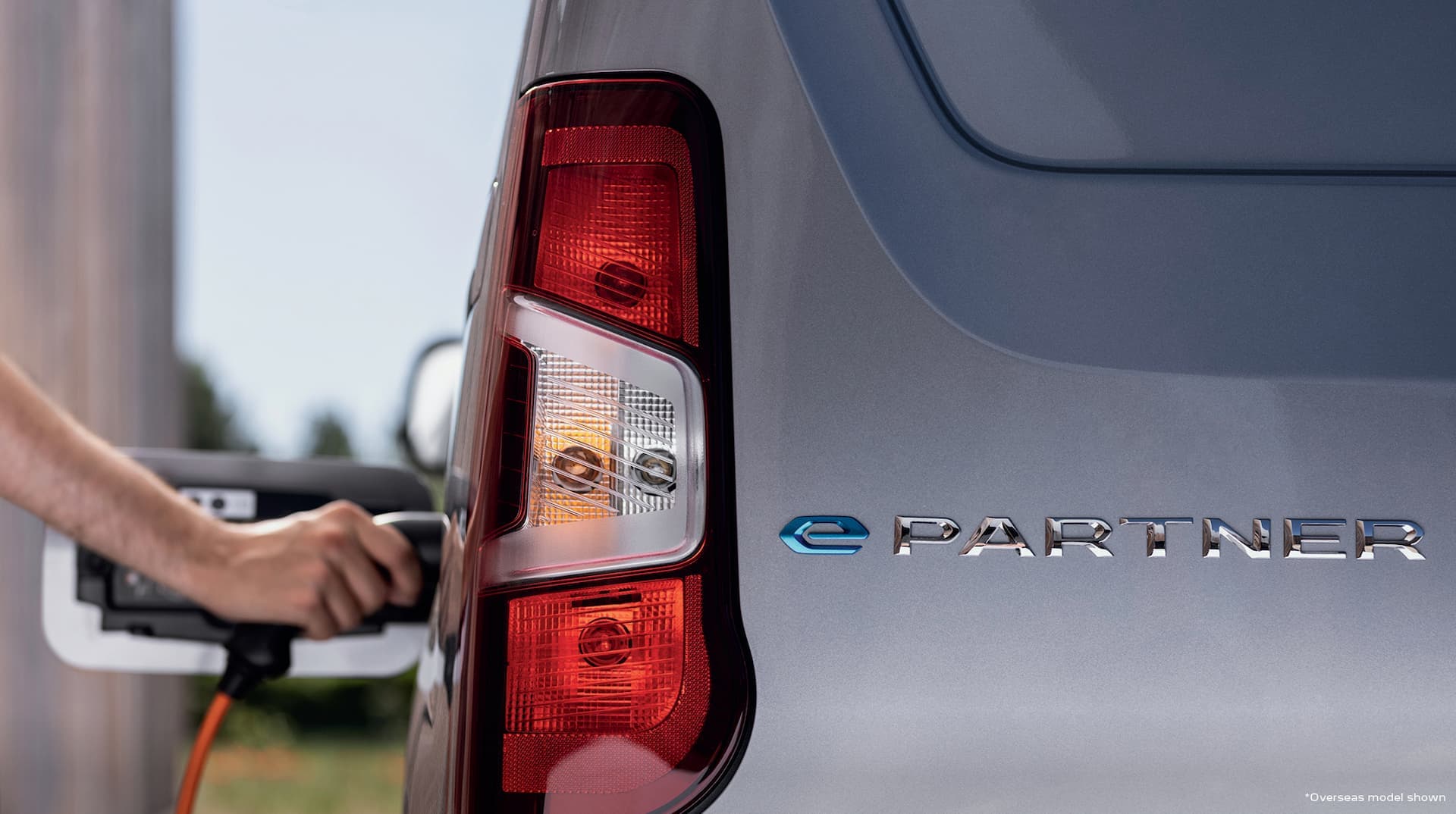 Person plugging in cable to Peugeot e-Partner van with e-Partner tailgate logo Person plugging in cable to Peugeot e-Partner van with e-Partner tailgate logo