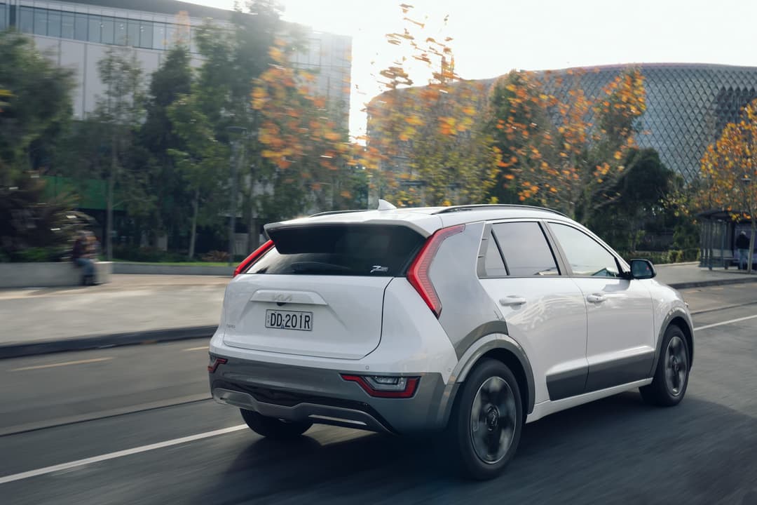 Kia Niro EV driving in city rear view Kia Niro EV driving in city rear view