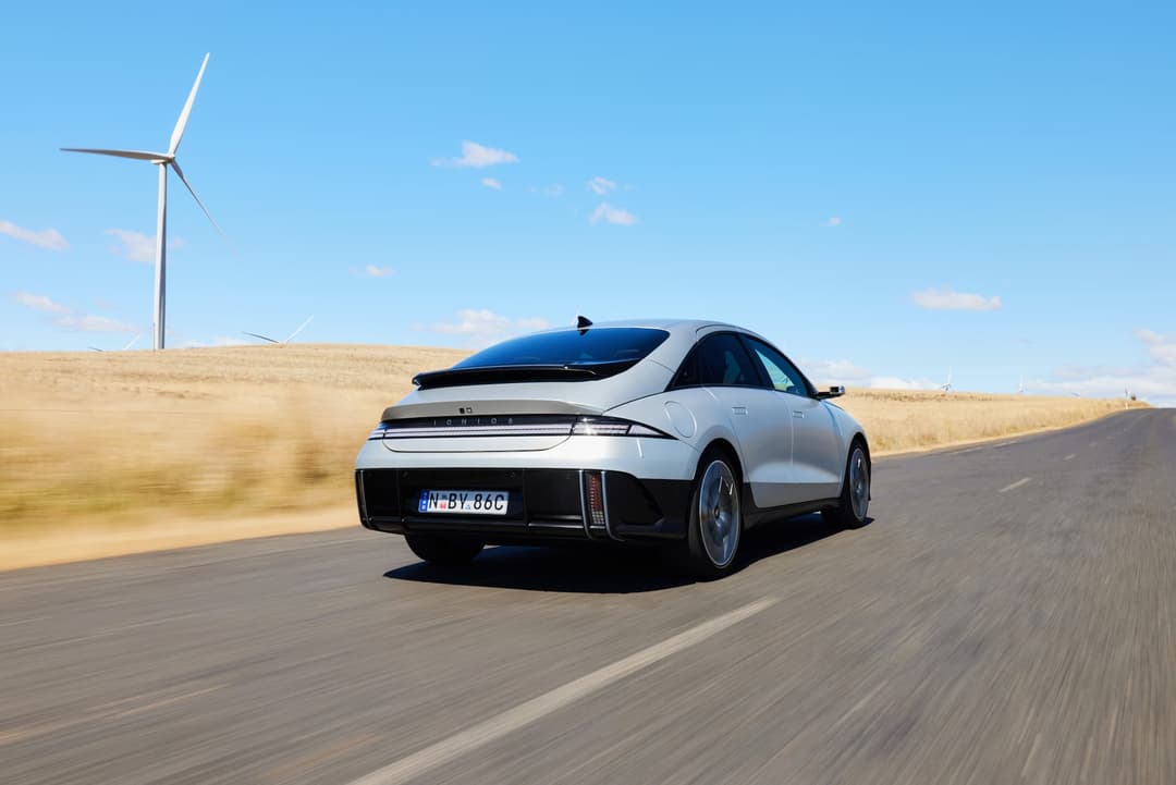 Silver Hyundai Ioniq 6 driving in rural Australia past wind turbine Silver Hyundai Ioniq 6 driving in rural Australia past wind turbine