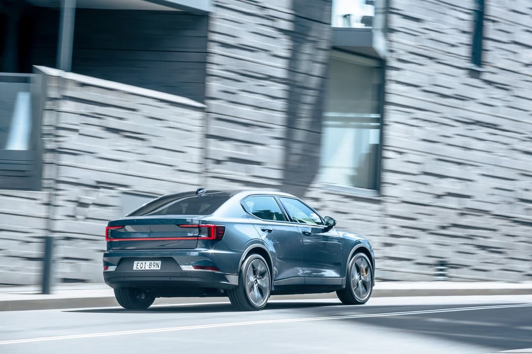 Blue Polestar 2 driving rear view Blue Polestar 2 driving rear view