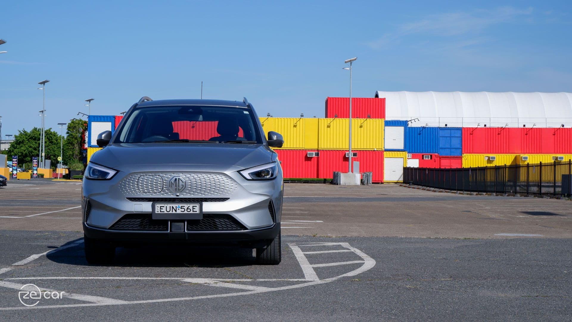 Silver MG ZS EV in front of colourful shipping containers Silver MG ZS EV in front of colourful shipping containers
