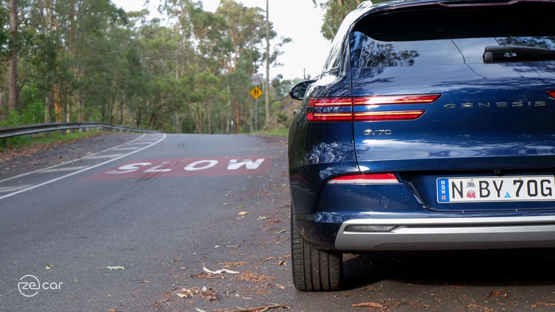 Genesis Electrified GV70 rear in front of 'slow' on road Genesis Electrified GV70 rear in front of 'slow' on road