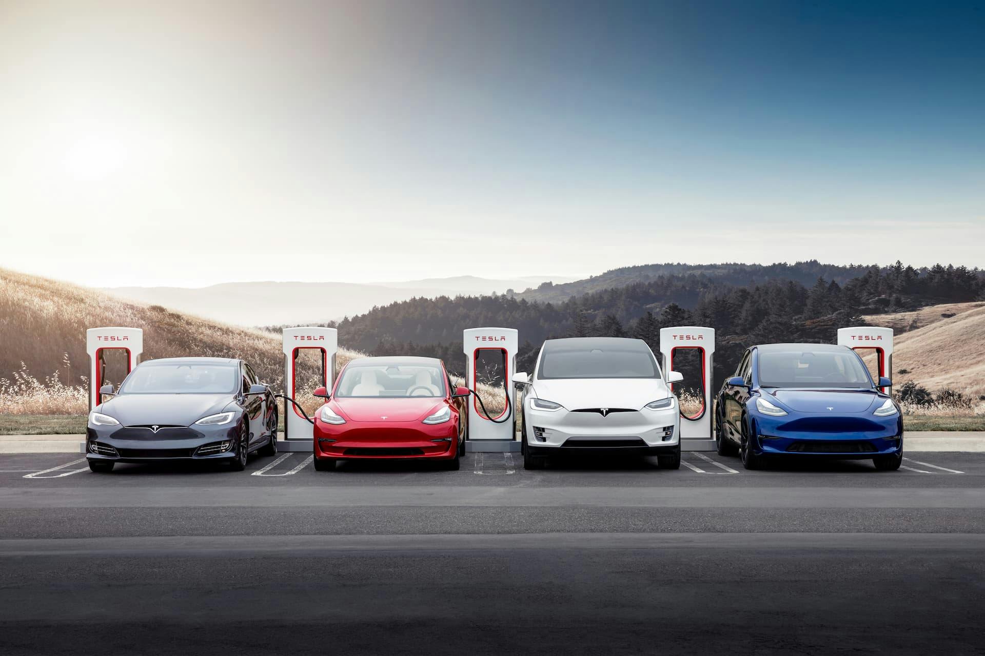 Four Tesla electric cars charging at Tesla Supercharging station