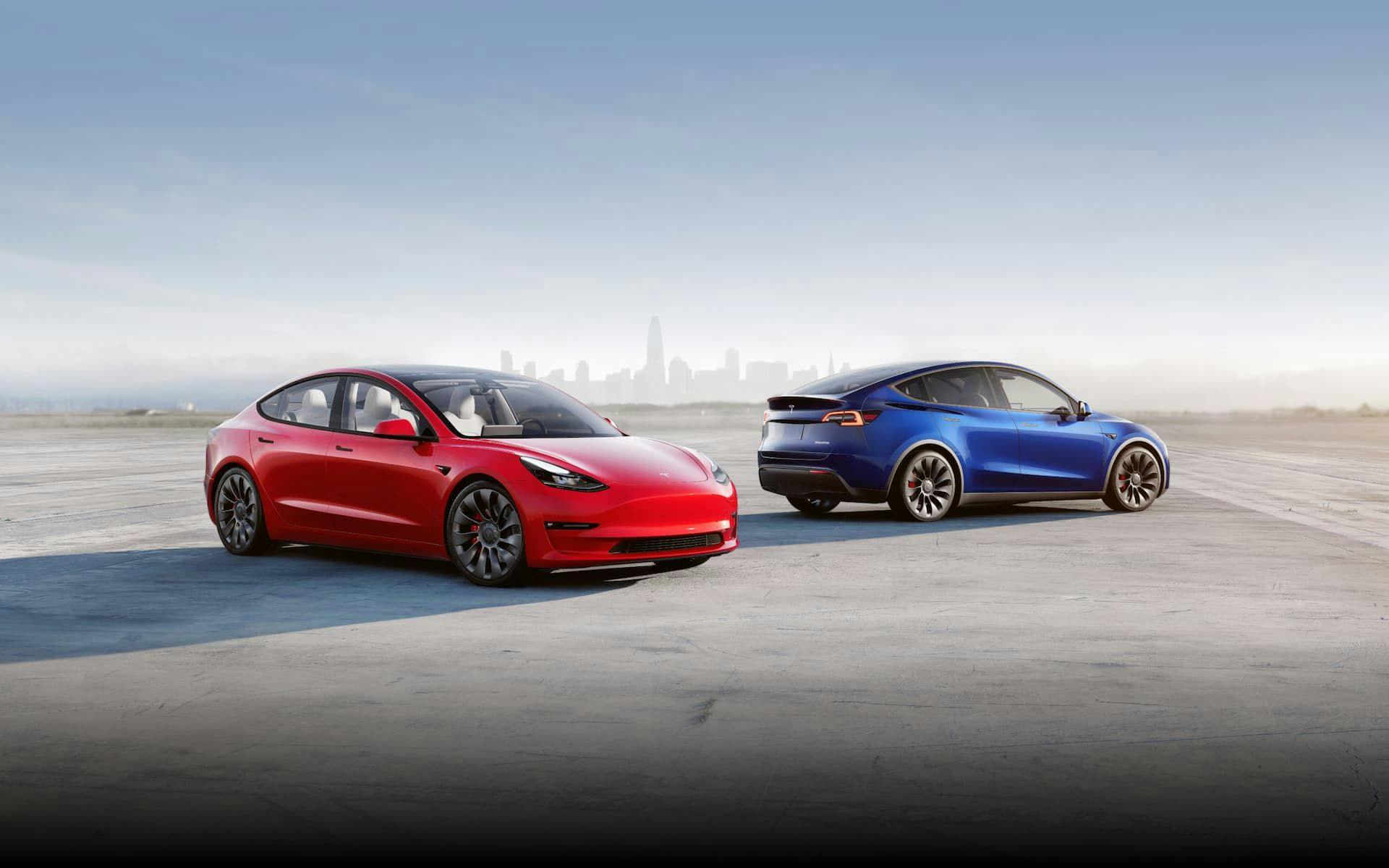 Red Tesla Model 3 Performance and blue Model Y Performance in front of city