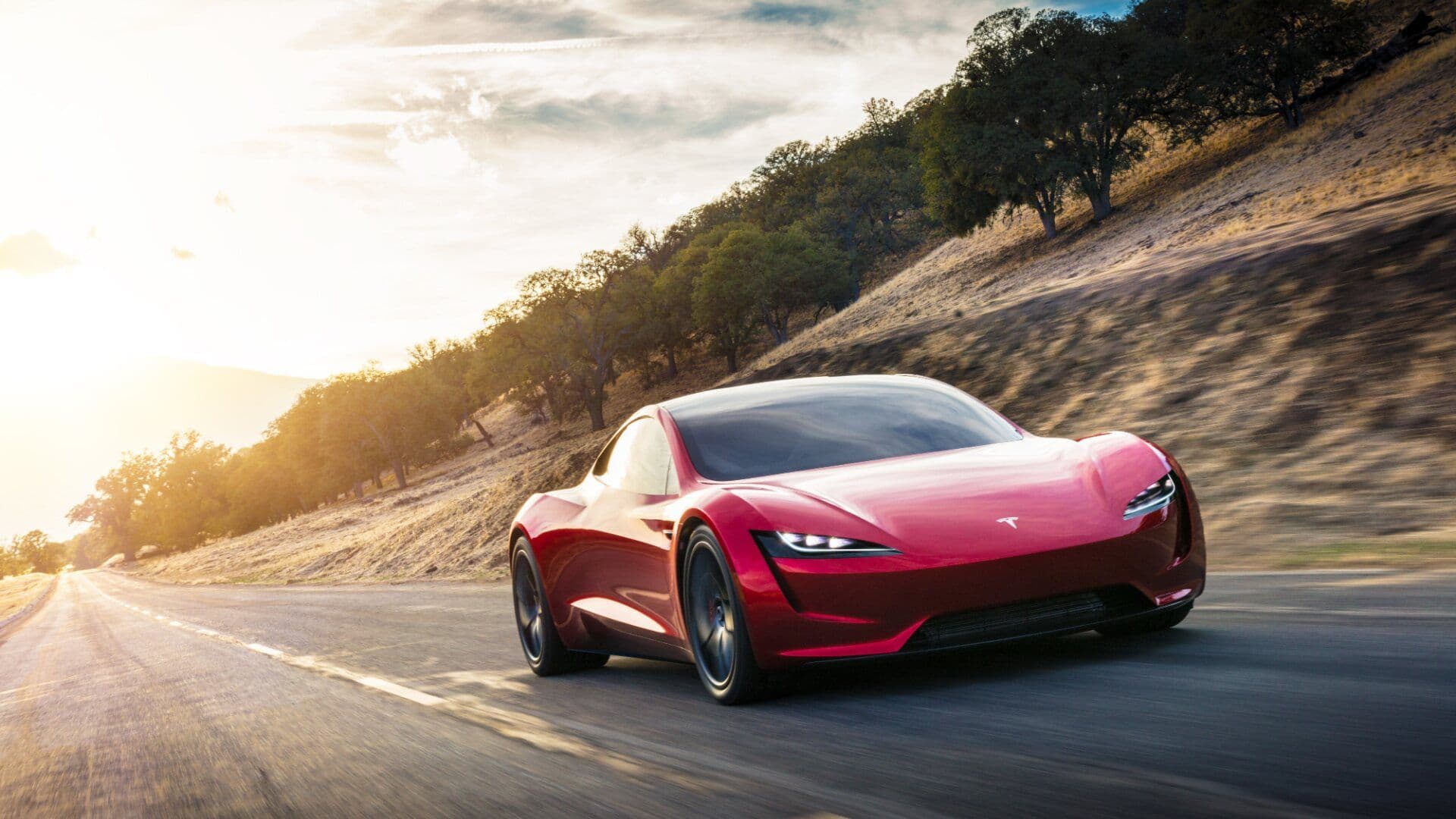 Tesla Roadster in red driving on road three quarter view Tesla Roadster in red driving on road three quarter view