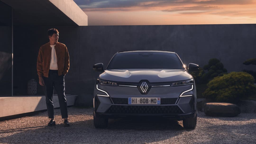 2024 Renault Megane E-Tech in grey front view parked at home with man standing 2024 Renault Megane E-Tech in grey front view parked at home with man standing