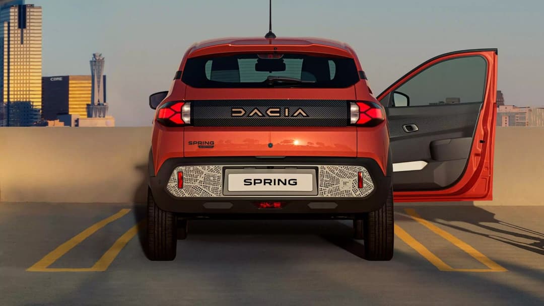 Dacia Spring in orange parked with passenger door opened rear view Dacia Spring in orange parked with passenger door opened rear view
