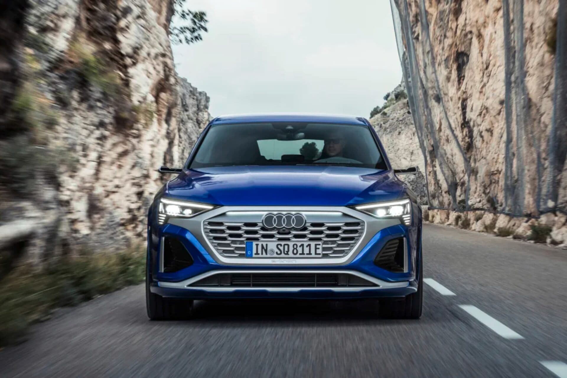 Audi SQ8 in blue front view driving on road Audi SQ8 in blue front view driving on road