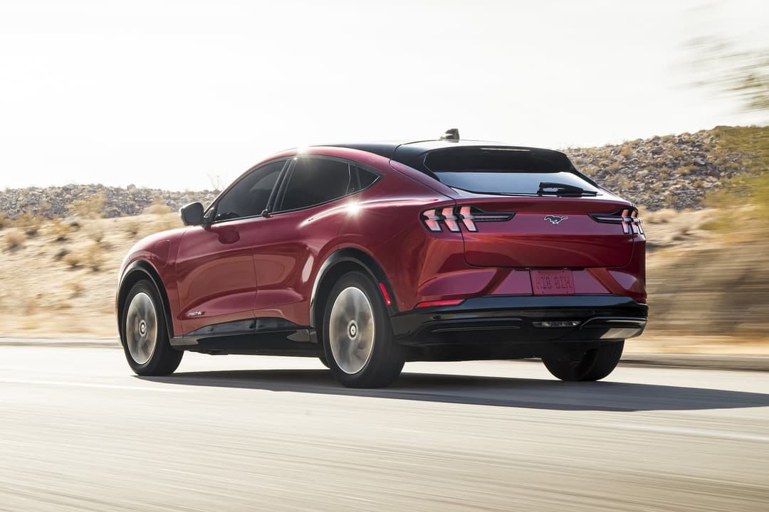 Ford Mustang Mach-E in red driving on road rear view Ford Mustang Mach-E in red driving on road rear view