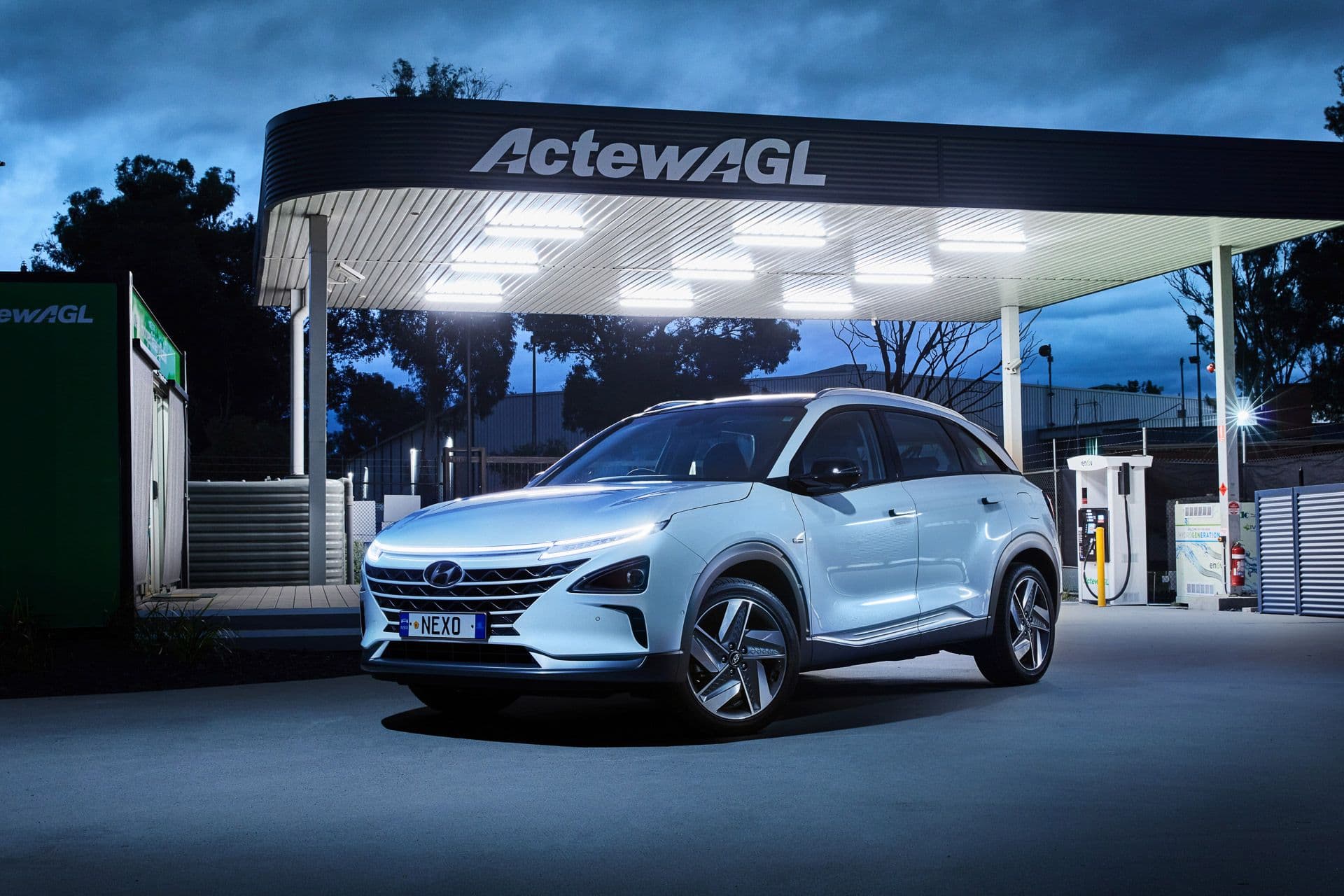 White Hyundai Nexo FCEV in front of ActewAGL hydrogen fuel pump at night White Hyundai Nexo FCEV in front of ActewAGL hydrogen fuel pump at night