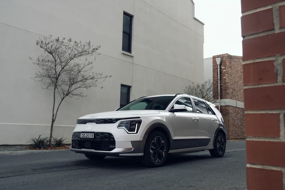 Kia Niro EV parked beside city apartments front view Kia Niro EV parked beside city apartments front view
