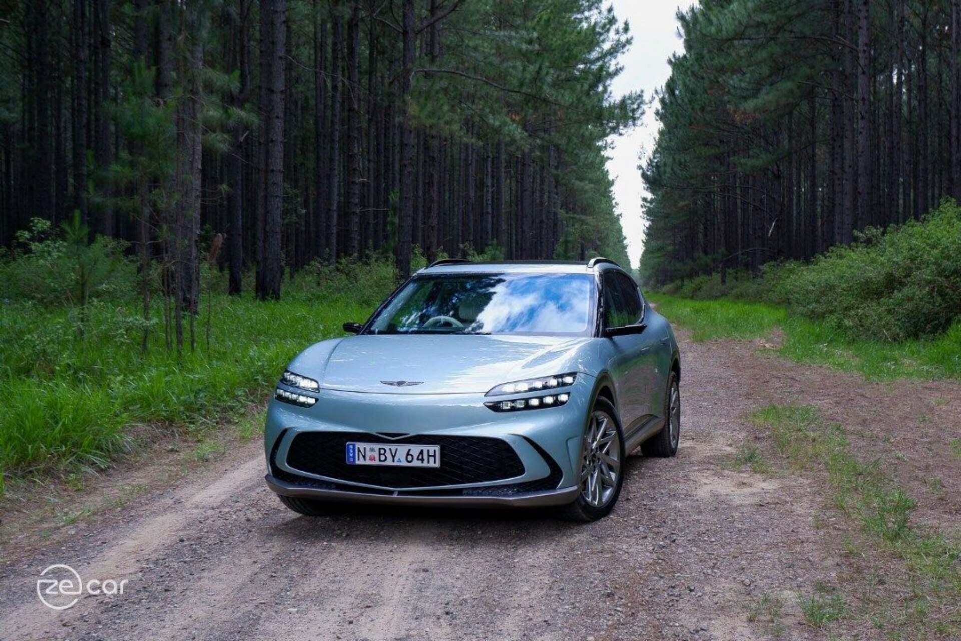 Genesis GV60 AWD fron view in forest trail Genesis GV60 AWD fron view in forest trail