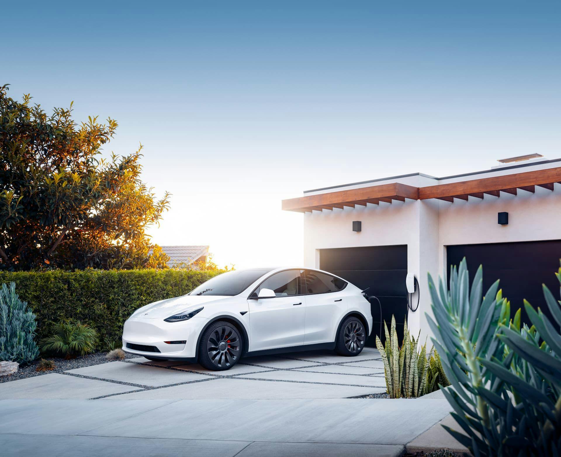 White Tesla Model Y Performance charging at home driveway