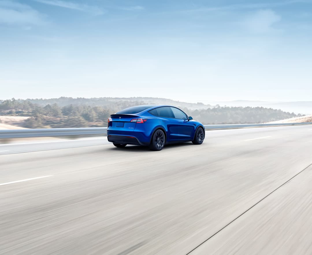 Blue Tesla Model Y driving rear view Blue Tesla Model Y driving rear view