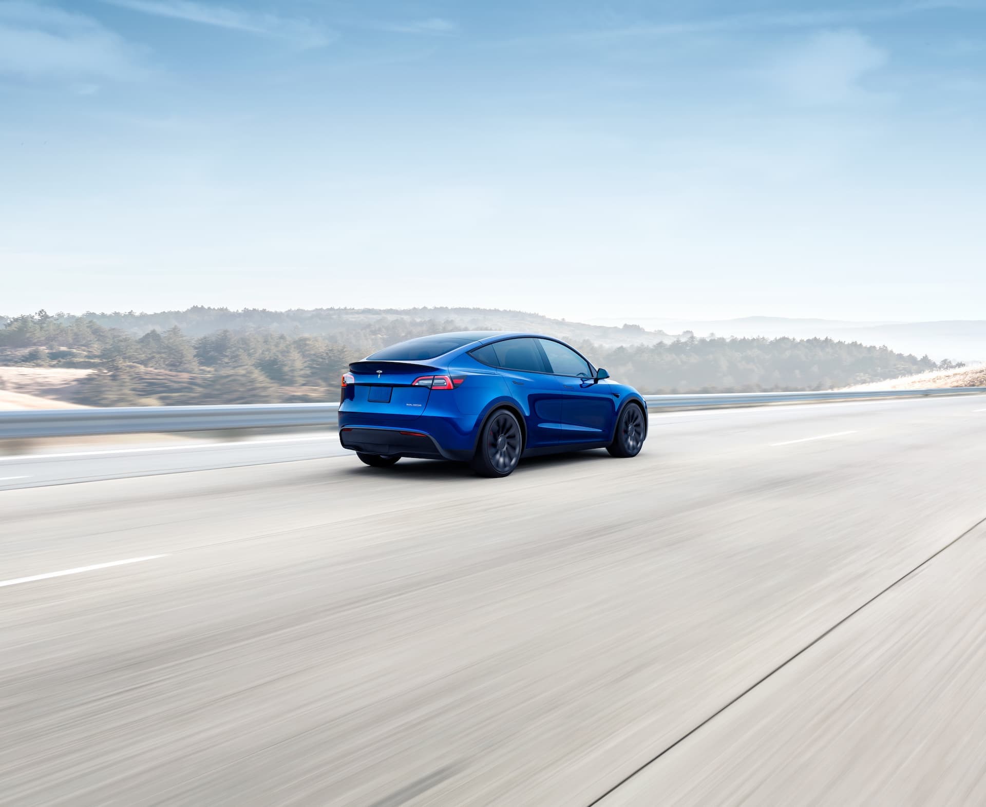 Blue Tesla Model Y driving rear view Blue Tesla Model Y driving rear view