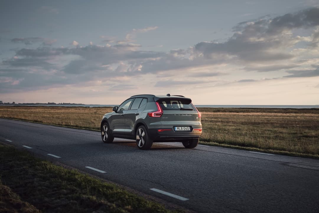 Green Volvo XC40 Recharge EV driving rear Green Volvo XC40 Recharge EV driving rear