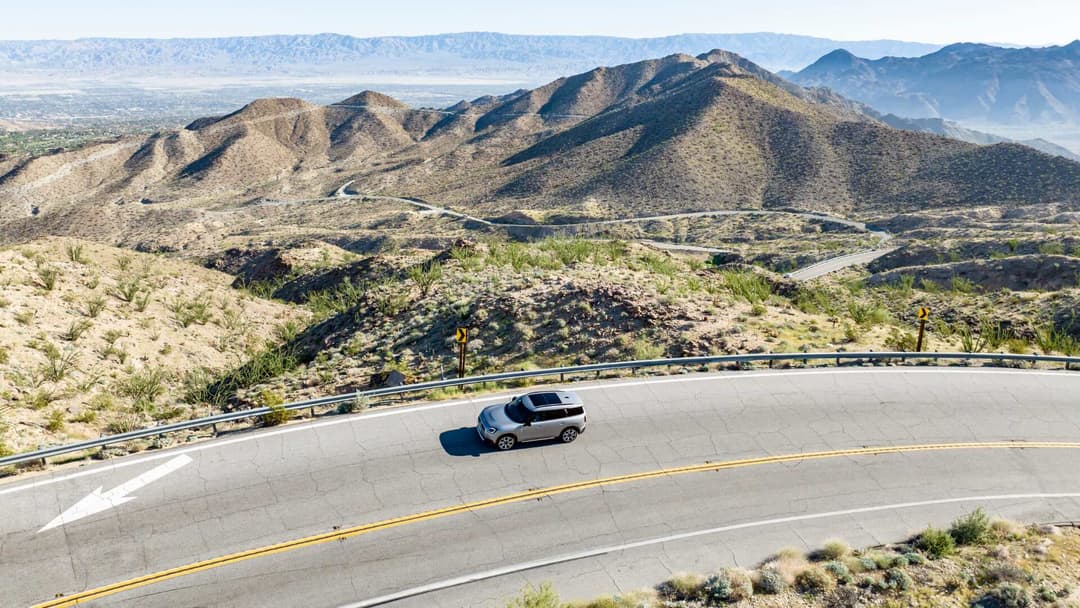 MINI Countryman driving on road with mountain range background top view MINI Countryman driving on road with mountain range background top view