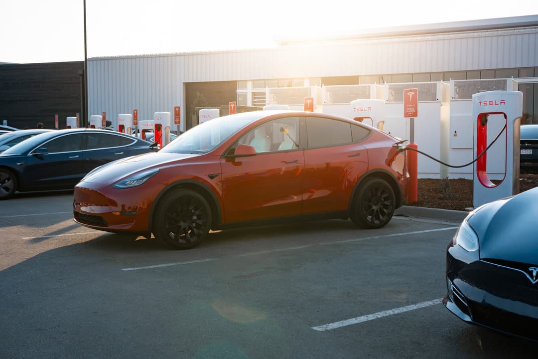Red Tesla Model Y with Induction wheels charging at Supercharger Red Tesla Model Y with Induction wheels charging at Supercharger