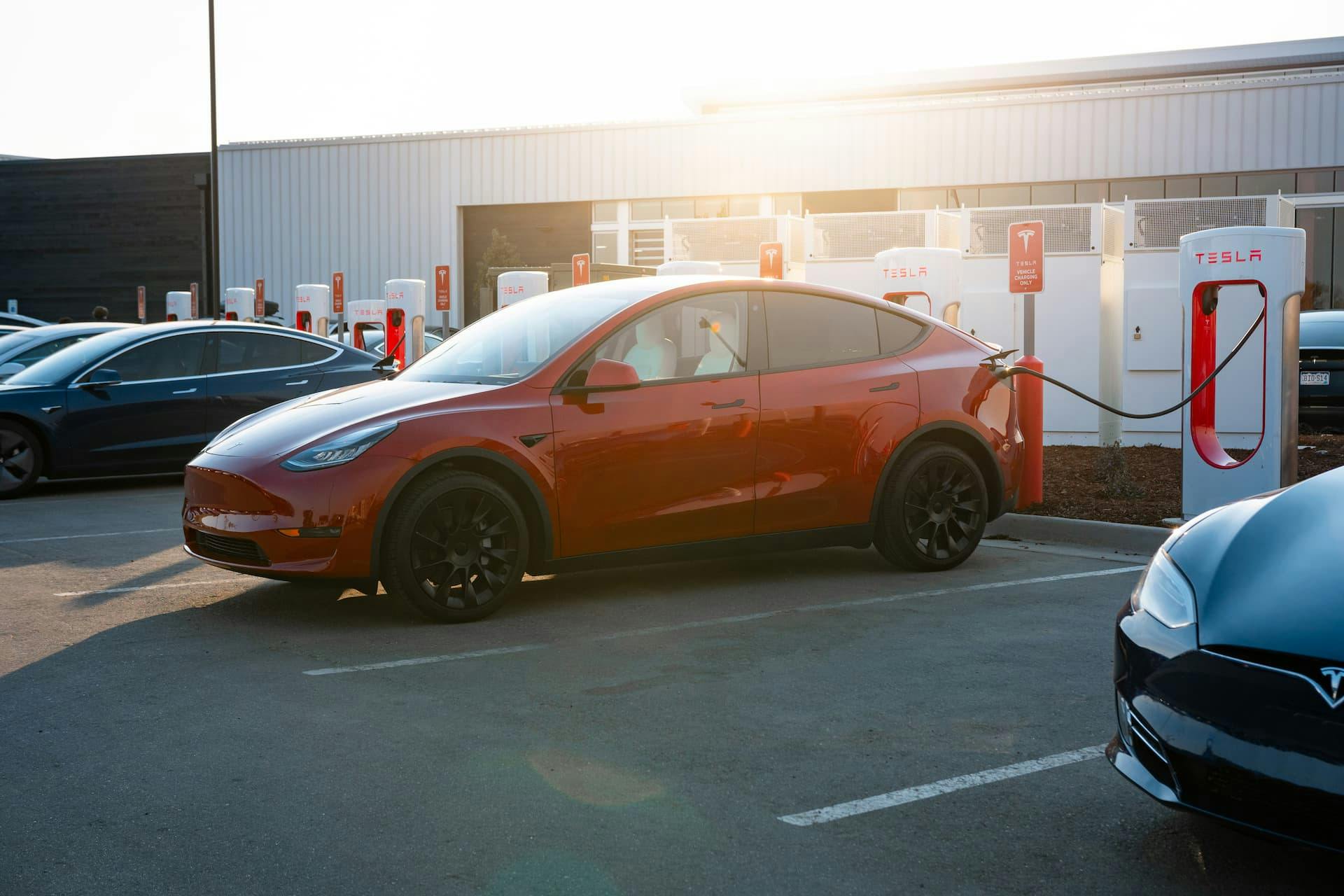 Red Tesla Model Y with Induction wheels charging at Supercharger